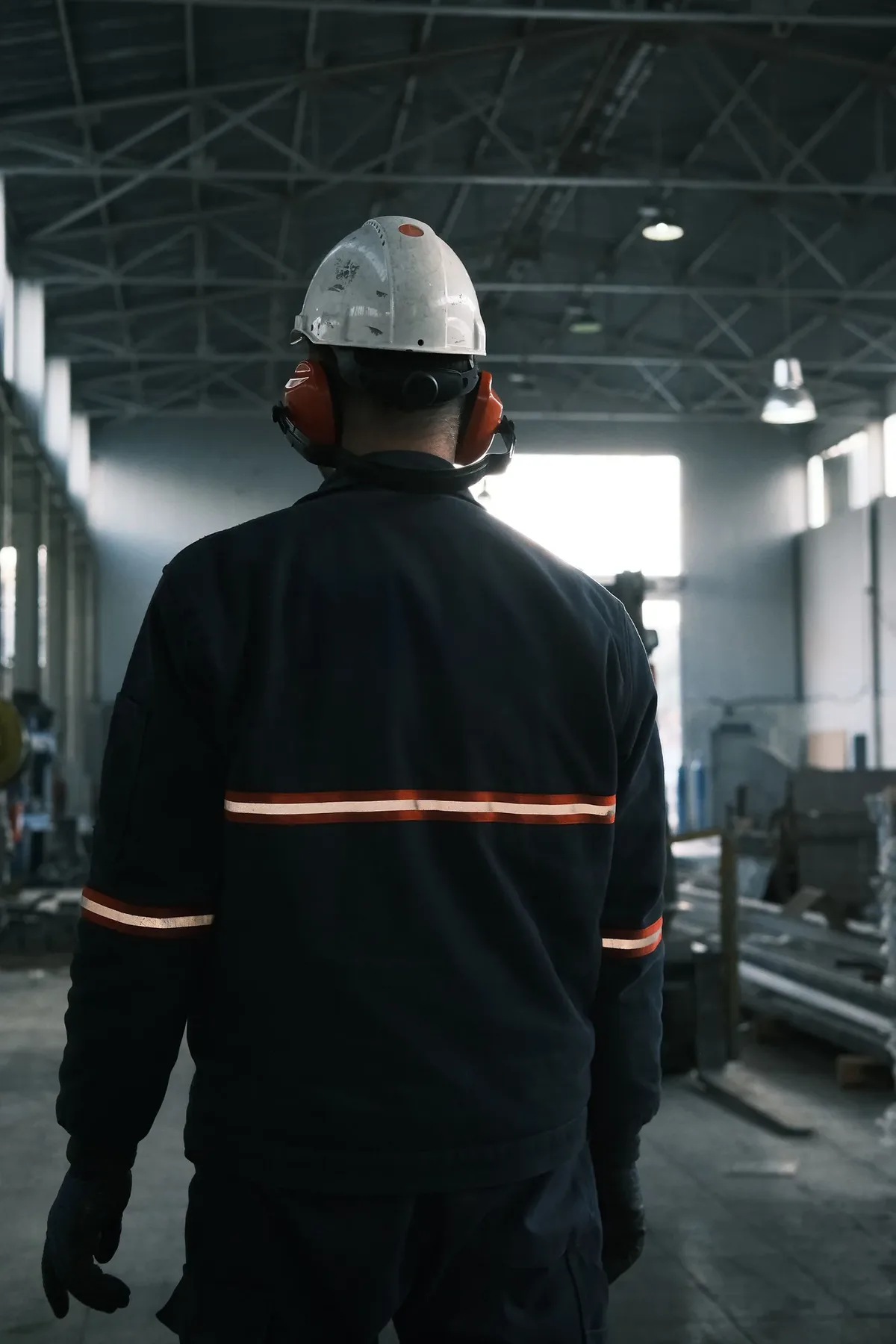 Trabajador de espaldas con ropa de seguridad en una planta industrial